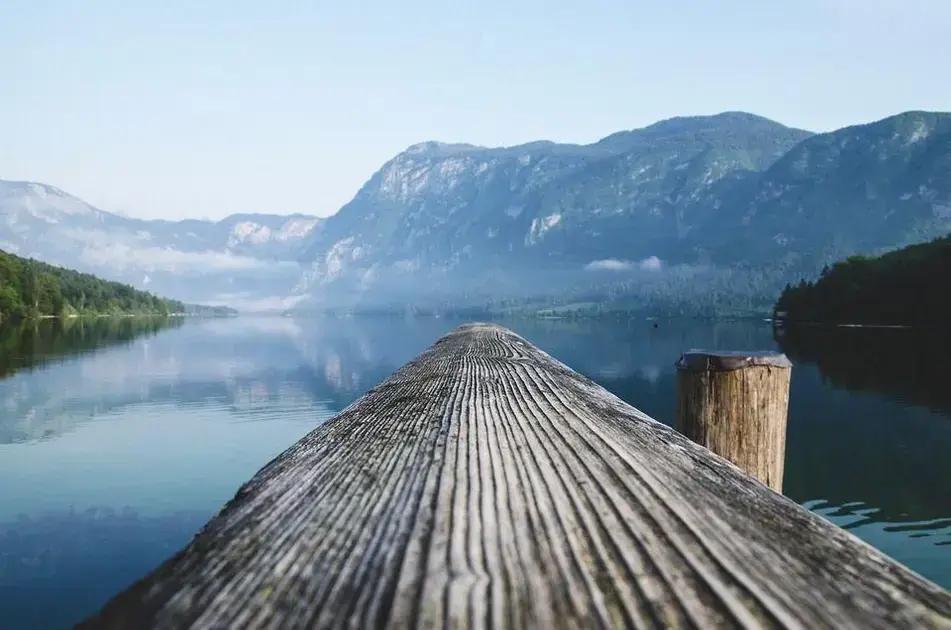 autocuidado para reduzir estresse e ansiedade: pier de madeira sobre lago calmo com montanhas ao fundo simbolizando silêncio mental e tranquilidade