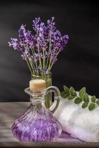Óleo essencial de lavanda: frasco de óleo essencial de lavanda em ambiente de spa com toalha e flores