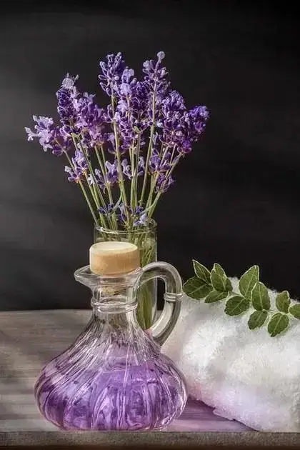 Óleo essencial de lavanda: frasco de óleo essencial de lavanda em ambiente de spa com toalha e flores