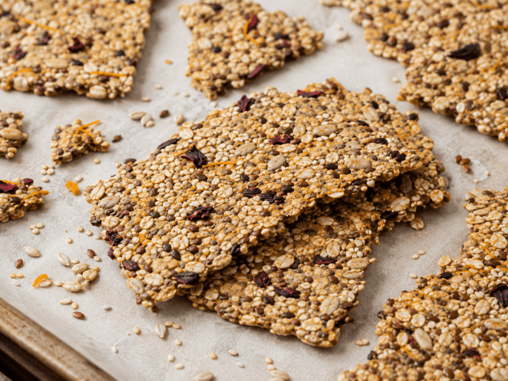 Crackers finos e dourados com sementes, aveia, hibisco e raspas de laranja após assar